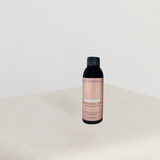 Bottle of skincare product on a white surface with a light gray background