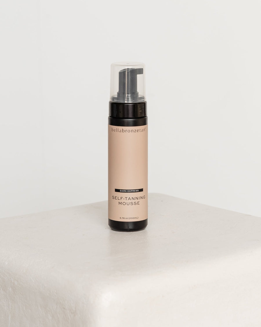 Self-tanning mousse bottle on a white surface with a white background