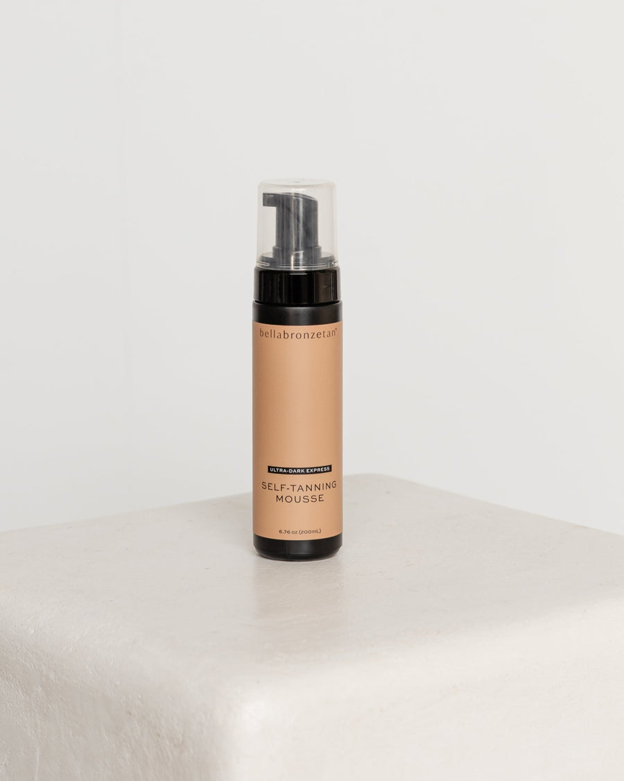 Self-tanning mousse bottle on a white surface with a light gray background